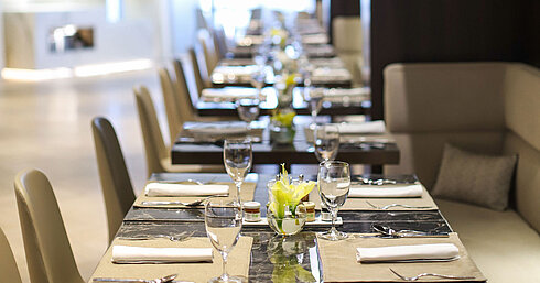 Reihe gedeckter Tische mit Gläsern und Blumen in elegantem Restaurant des Maritim Hotel Plaza Tirana