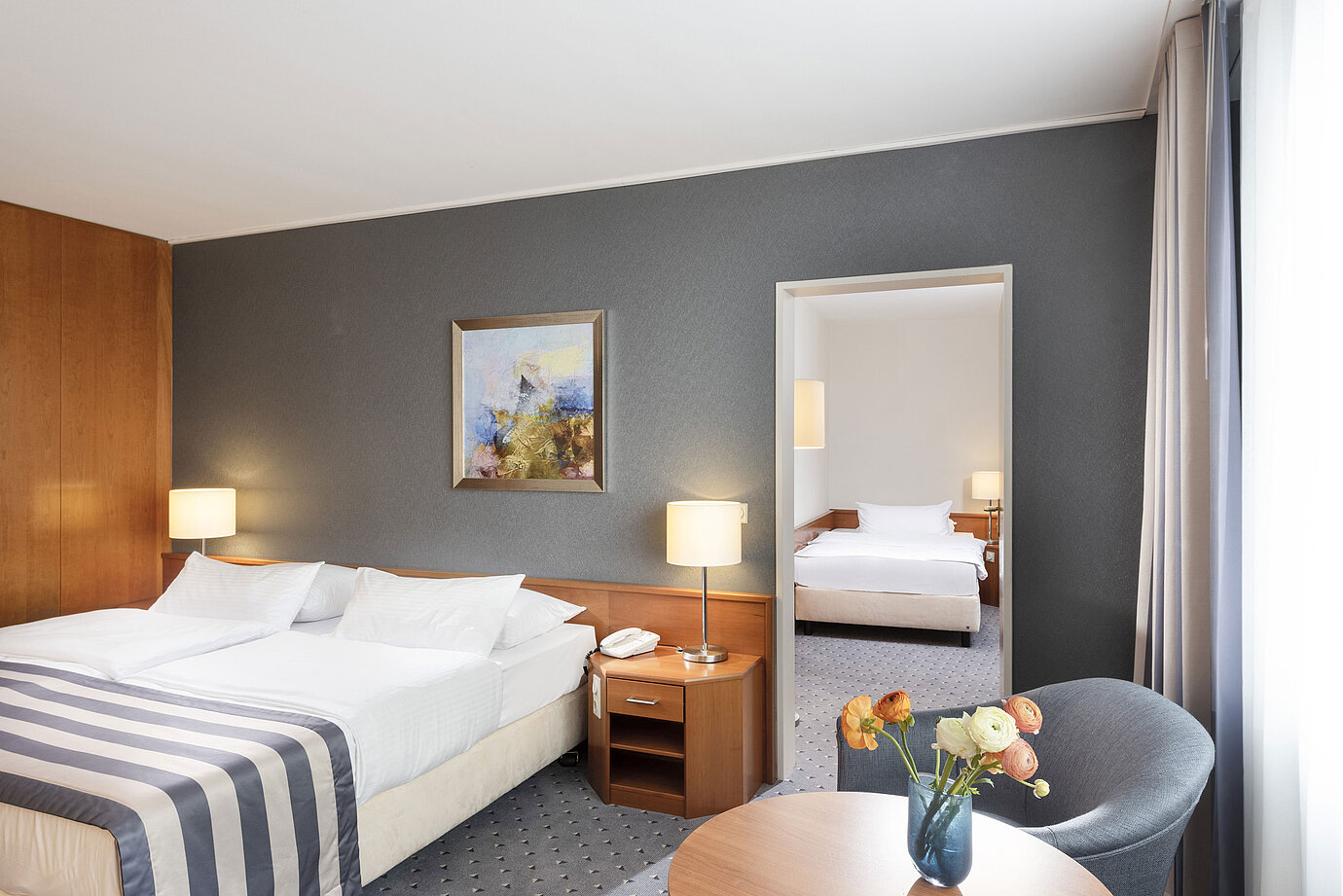 Familienzimmer im Maritim Hotel Ulm mit Doppelbett, Sitzecke und stilvoller Spiegelwand