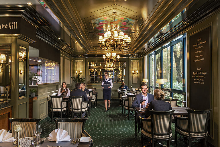  Gäste im eleganten Restaurant L'Echalote des Maritim Hotels Bremen genießen feine Speisen in stilvollem Ambiente.