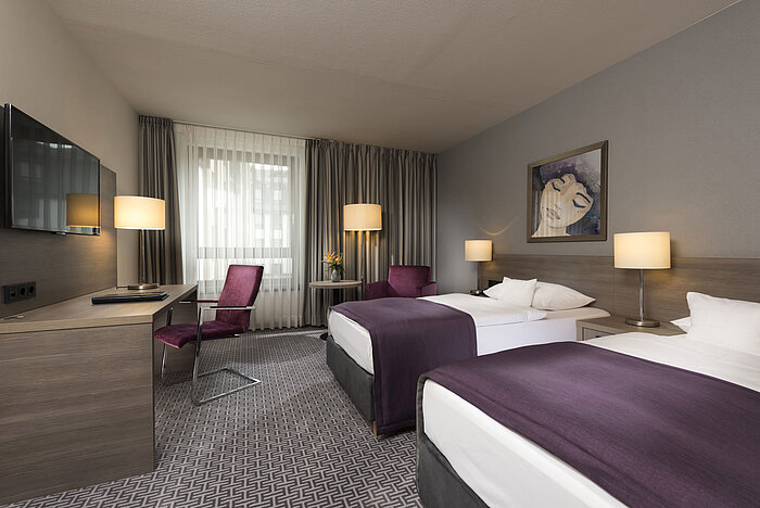 Modernes Doppelzimmer im Maritim Hotel Königswinter mit zwei Betten, Schreibtisch und stilvoller Einrichtung.