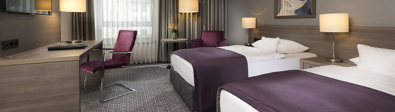 Modernes Doppelzimmer im Maritim Hotel Königswinter mit zwei Betten, Schreibtisch und stilvoller Einrichtung.