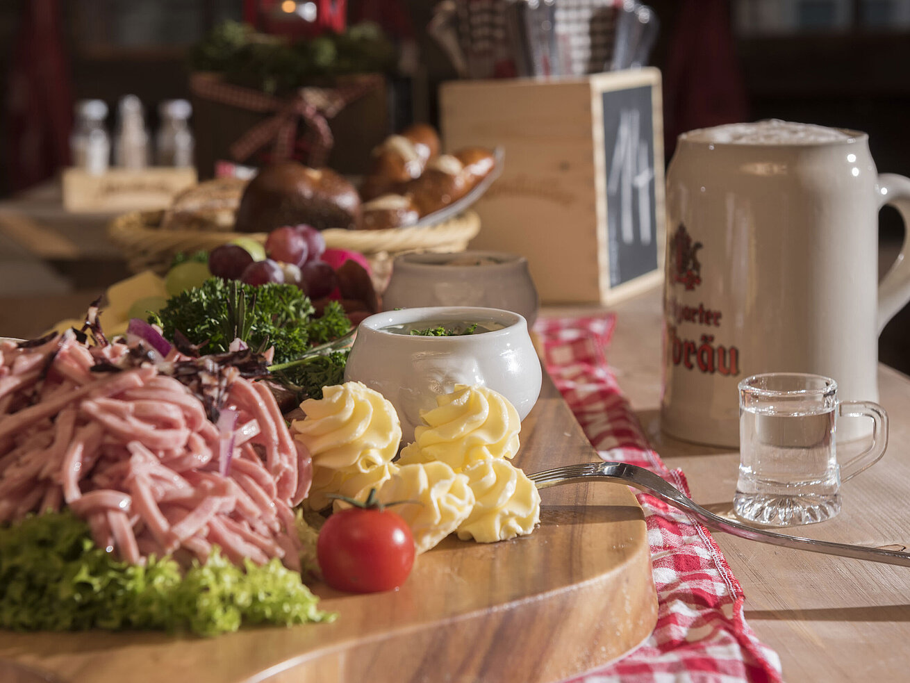 Bayerischer Wurstsalat, Butterrosen, Trauben und Bierkrug auf Holzplatte in der Maritim Alm Stuttgart