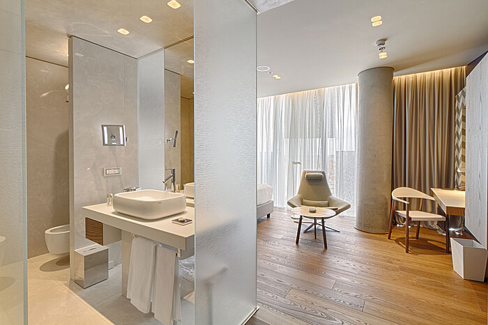 Modernes Hotelzimmer mit offenem Badkonzept, Holzfußboden und Designmöbeln im Maritim Hotel Plaza Tirana