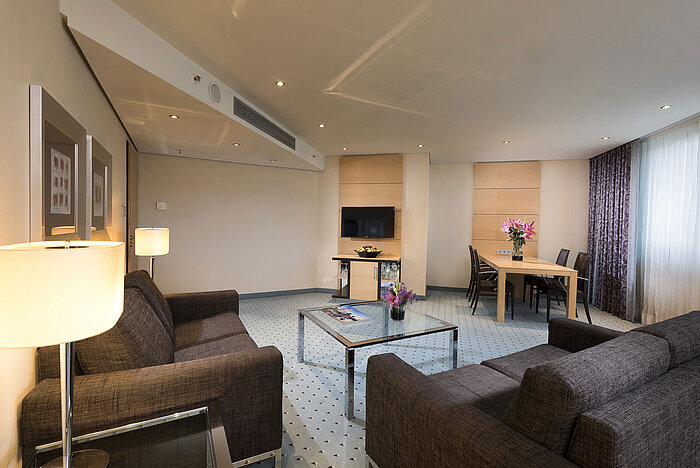 Geräumige Suite im Maritim Hotel Düsseldorf mit modernem Wohnbereich, Esstisch, Sofas und stilvoller Dekoration.