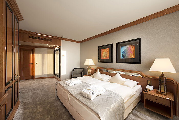 Komfortables Schlafzimmer im Maritim Hotel Ulm mit Doppelbett, Holzdetails und bereitgelegten Bademänteln