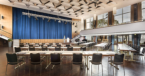 Großer Saal „Maritim“ im Maritim Seehotel Timmendorfer Strand mit Bühne, blauen Vorhängen und Bestuhlung für Tagungen.