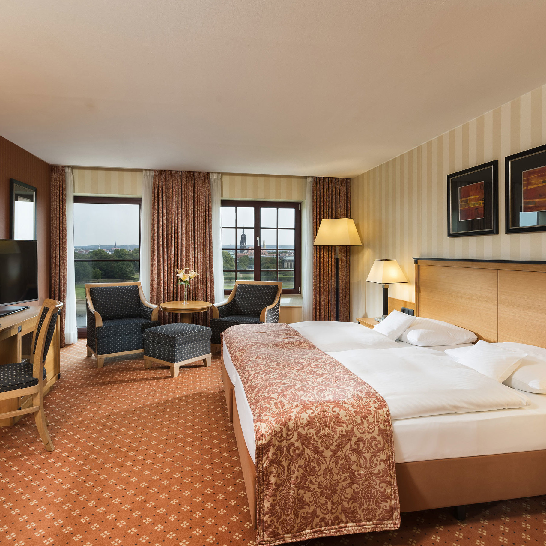 Superior Zimmer im Maritim Hotel Dresden mit elegantem Doppelbett, Schreibtisch und Sitzbereich sowie Blick auf die Stadt.