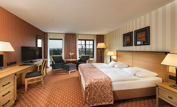 Superior Zimmer im Maritim Hotel Dresden mit elegantem Doppelbett, Schreibtisch und Sitzbereich sowie Blick auf die Stadt.