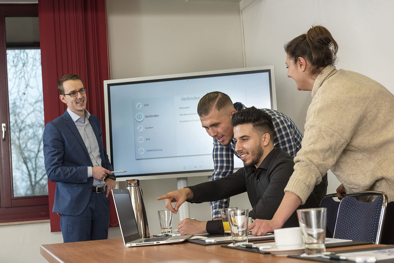 Team-Meeting im Salon Rhein im Maritim Köln mit einem Bildschirm, Laptops und Teilnehmern, die zusammenarbeiten.