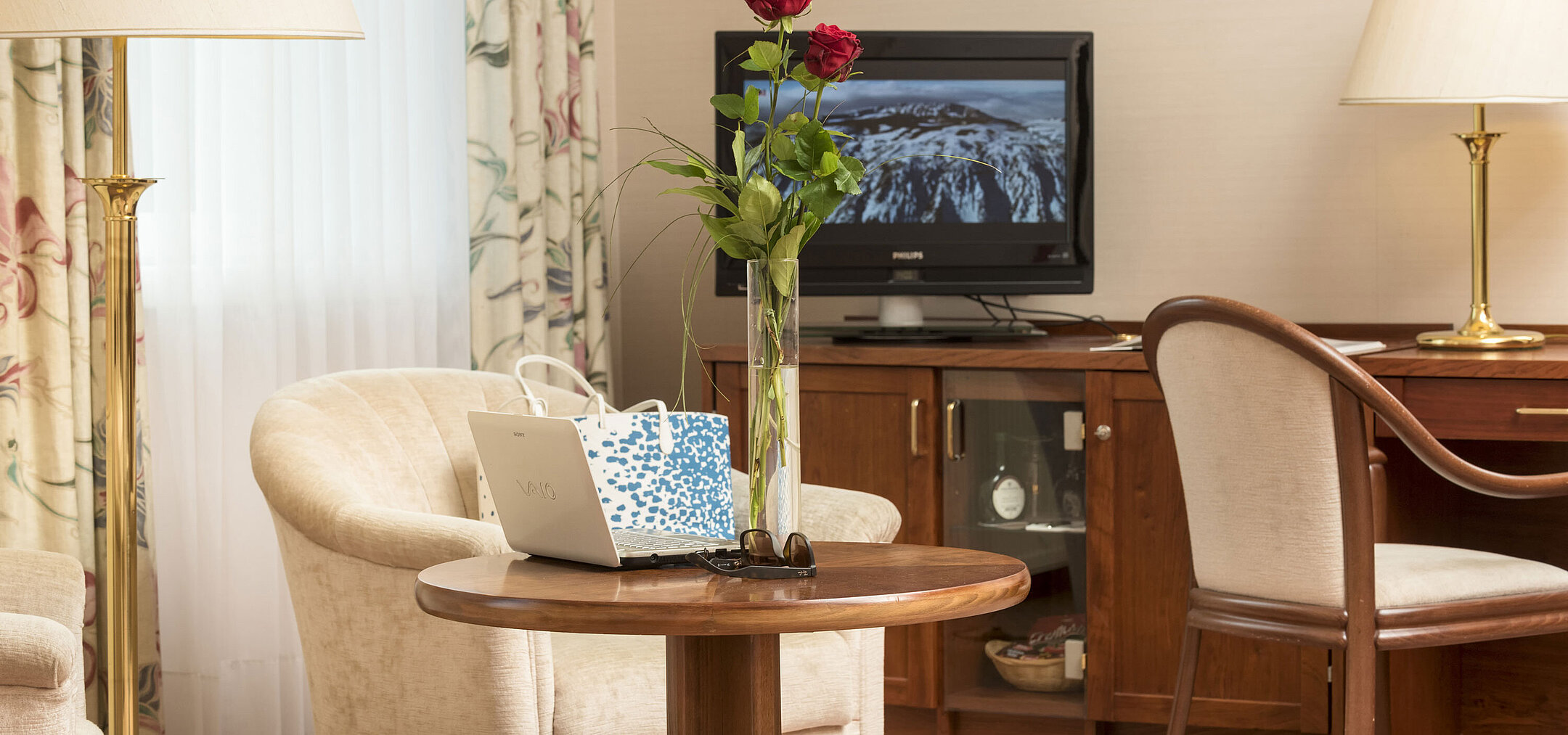 Gemütlicher Sitzbereich mit Rosen, Laptop und TV im Zimmer des Maritim Hotel Bad Wildungen