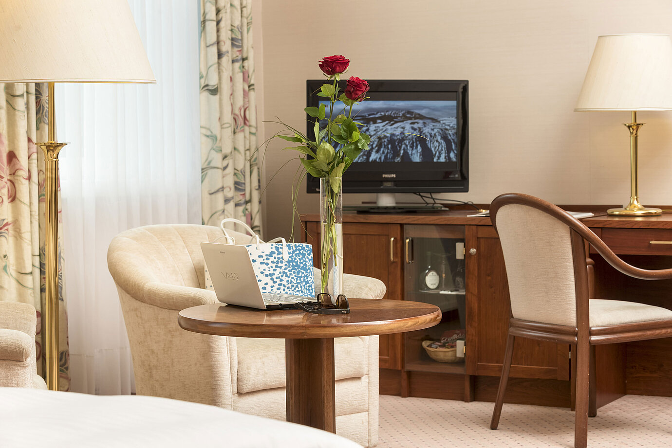 Gemütlicher Sitzbereich mit Rosen, Laptop und TV im Zimmer des Maritim Hotel Bad Wildungen