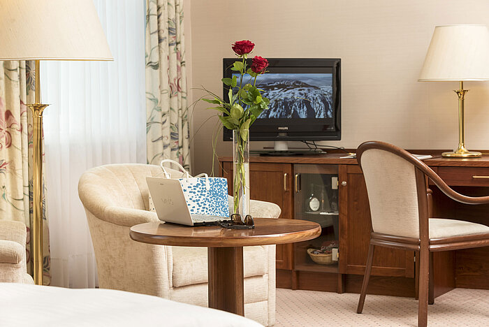 Gemütlicher Sitzbereich mit Rosen, Laptop und TV im Zimmer des Maritim Hotel Bad Wildungen