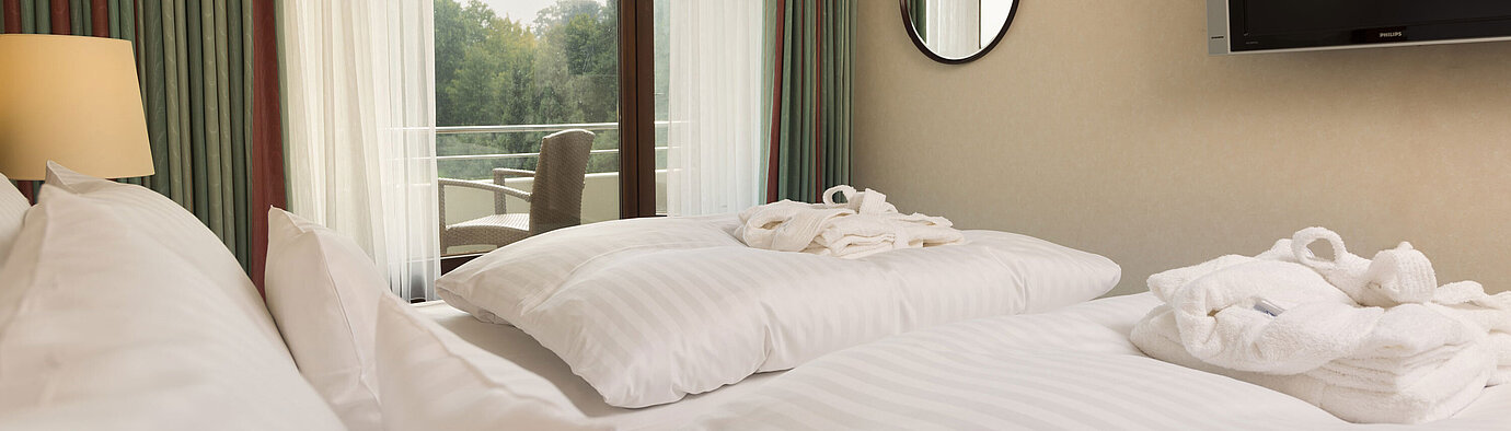 Junior Suite Doppelbett mit TV, Bademantel und Ausblick auf den Balkon im Maritim Hotel Bad Salzuflen