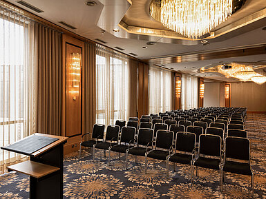 Großer Konferenzsaal mit Reihenbestuhlung, Rednerpult und Kronleuchtern im Maritim Hotel Ulm.
