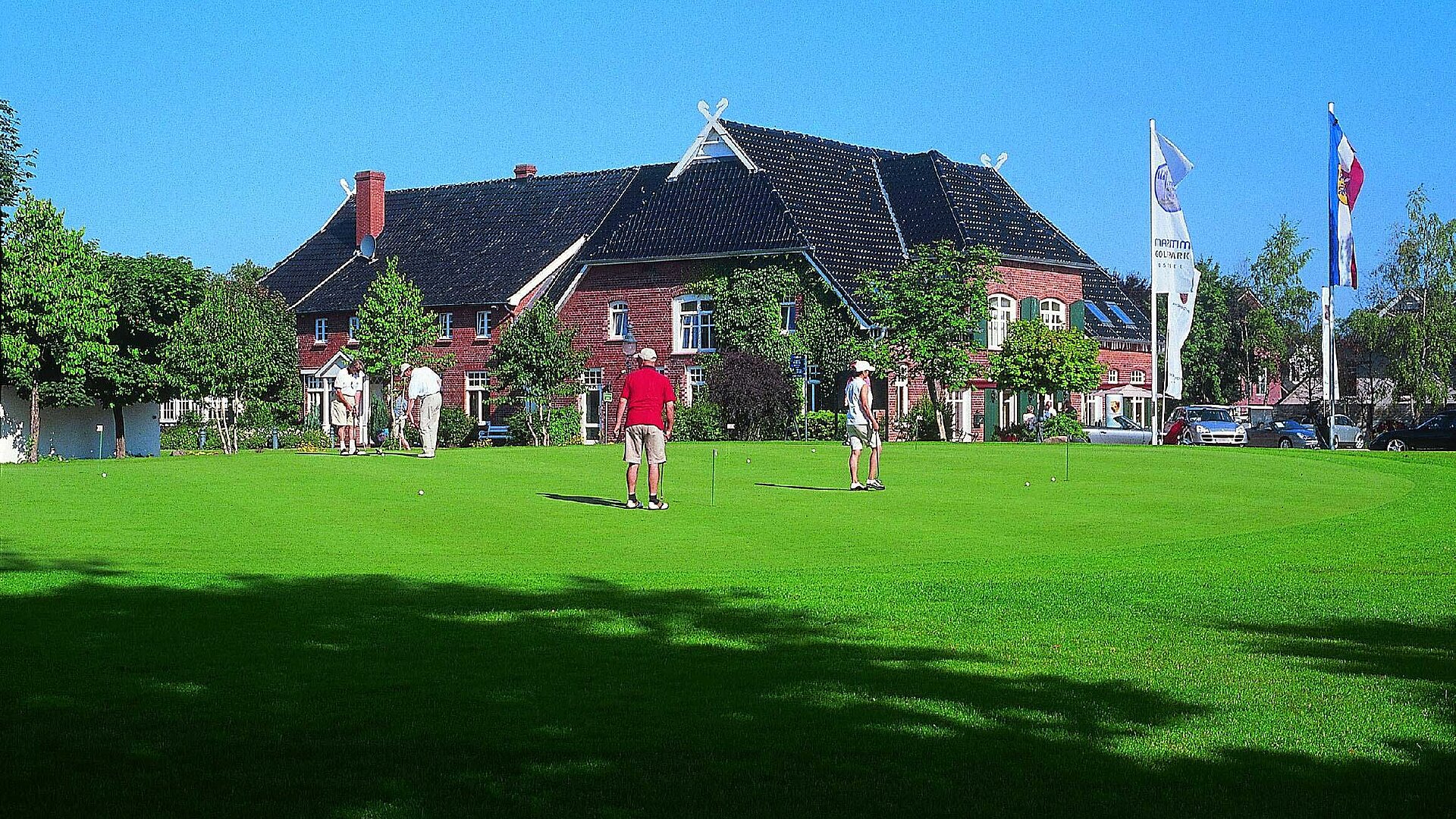 Spieler auf dem Rasen des Maritim Golfparks vor dem Clubhaus bei sonnigem Wetter