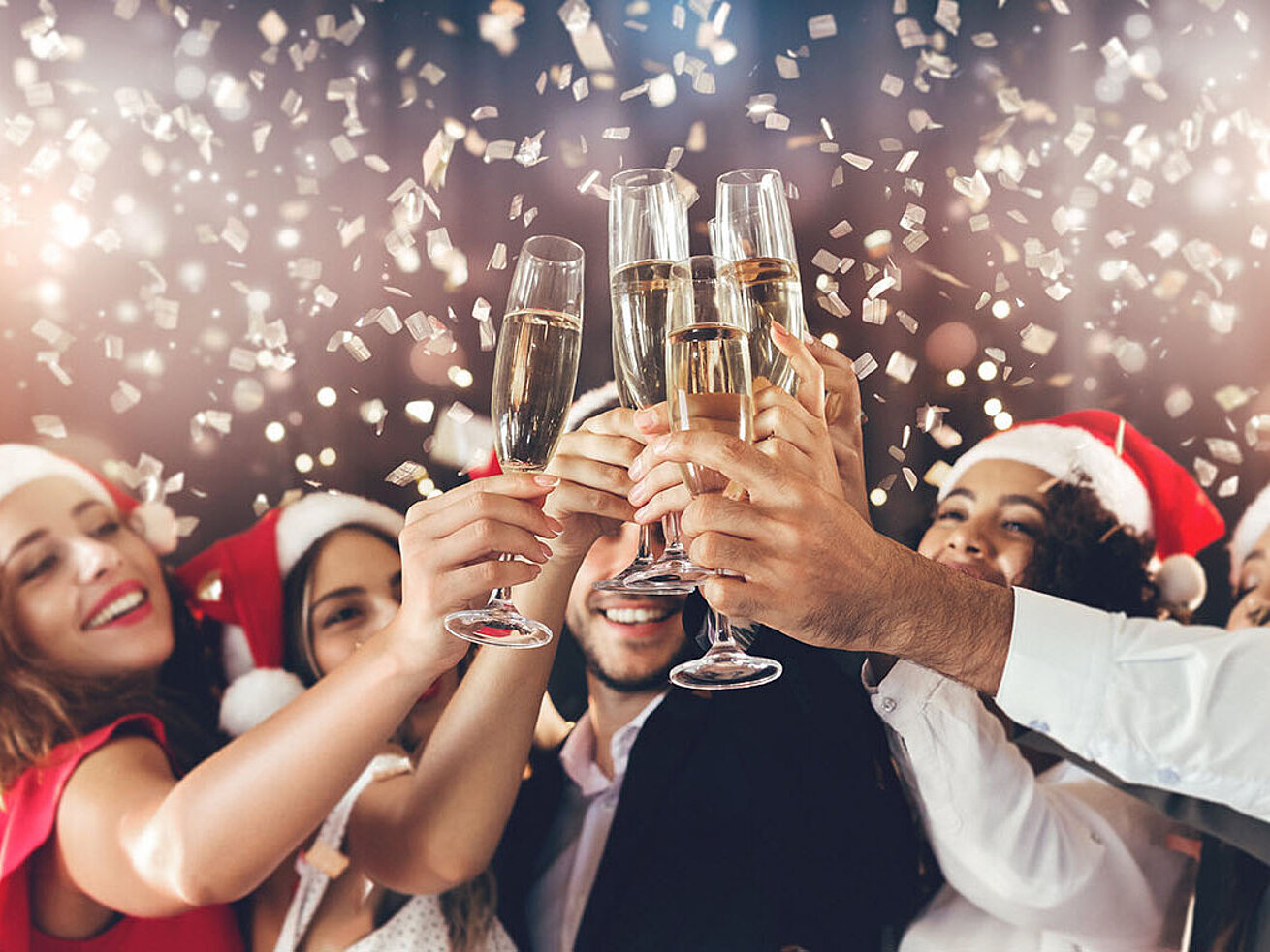 Menschen stoßen bei einer festlichen Weihnachtsfeier mit Sekt an – fröhliche Stimmung in weihnachtlichem Ambiente