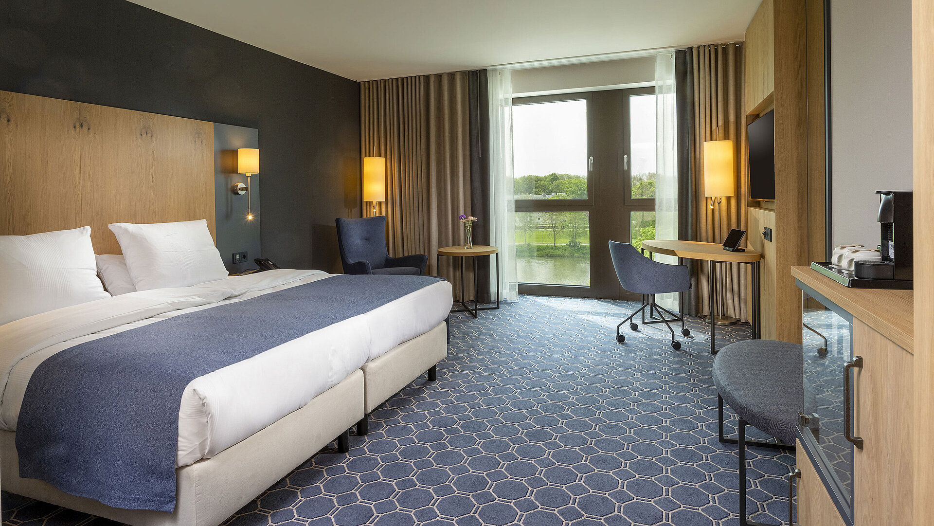 Geräumiges Doppelzimmer im Maritim Hotel Ingolstadt mit großem Bett, Schreibtisch und Blick auf den Fluss.