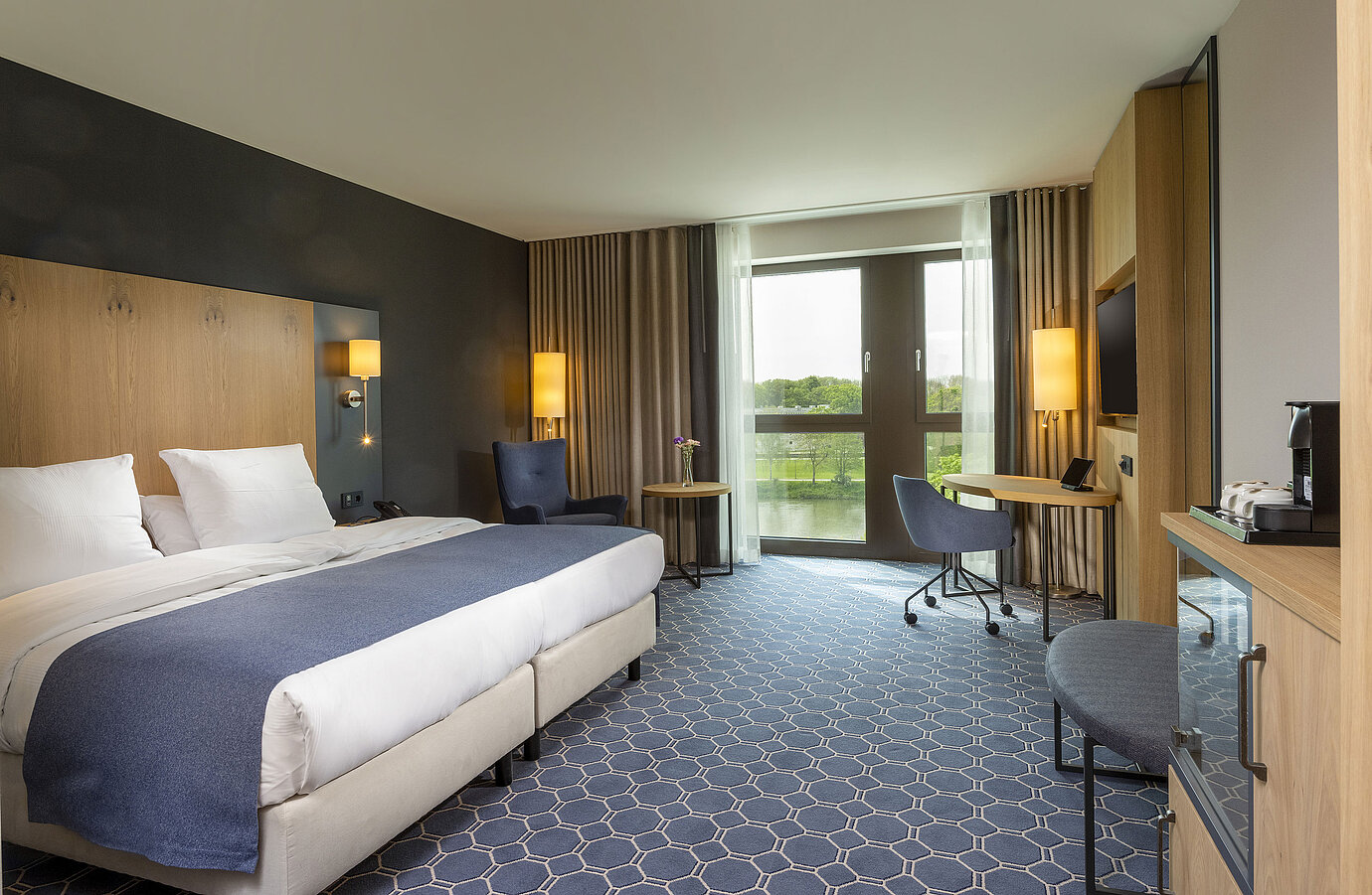 Geräumiges Doppelzimmer im Maritim Hotel Ingolstadt mit großem Bett, Schreibtisch und Blick auf den Fluss.