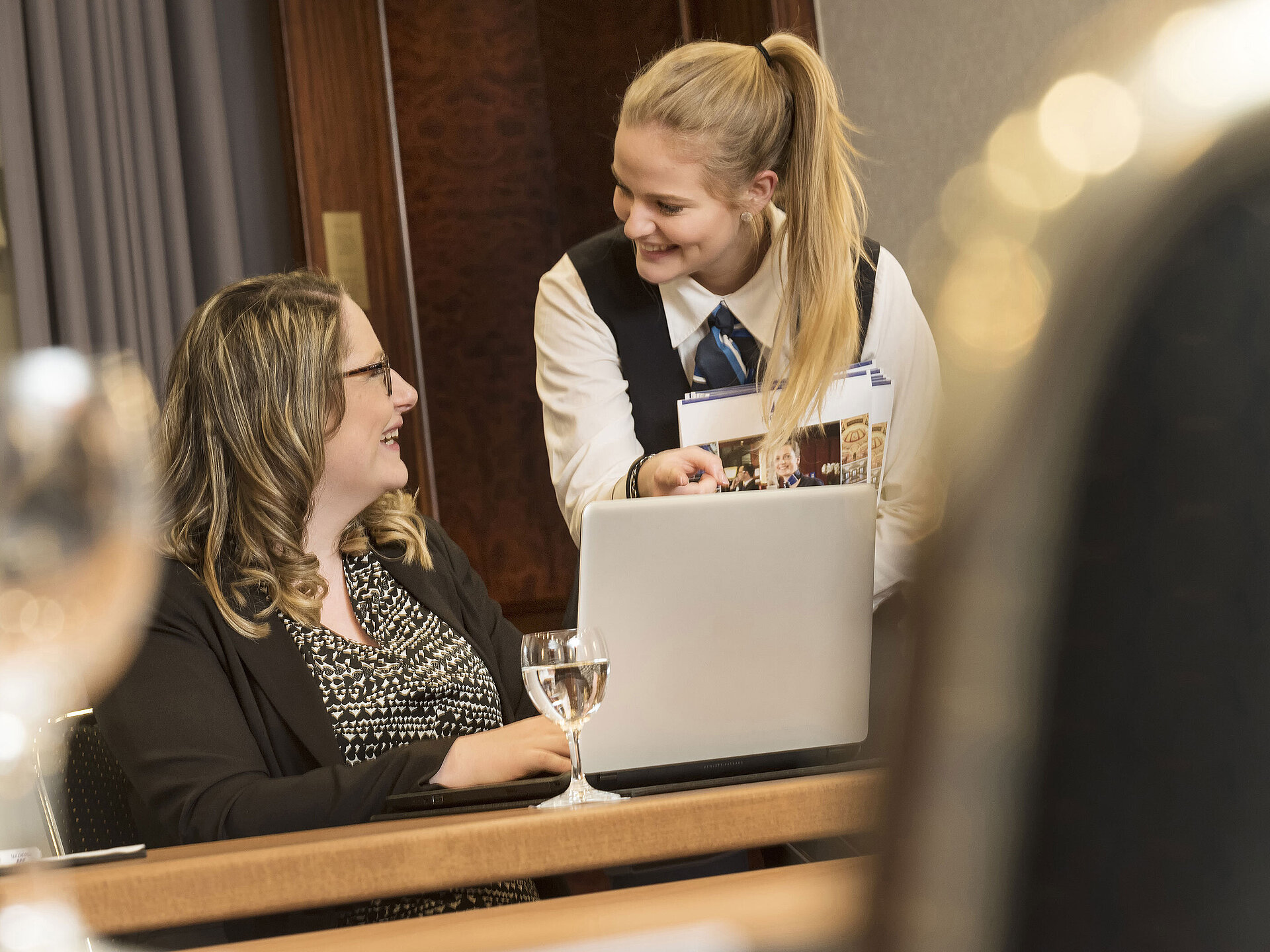Maritim Tagungsservice Mitarbeiterin des Maritim Hotel Bonn bietet einer Teilnehmerin während eines Meetings im Salon Rheinaue Unterstützung an.