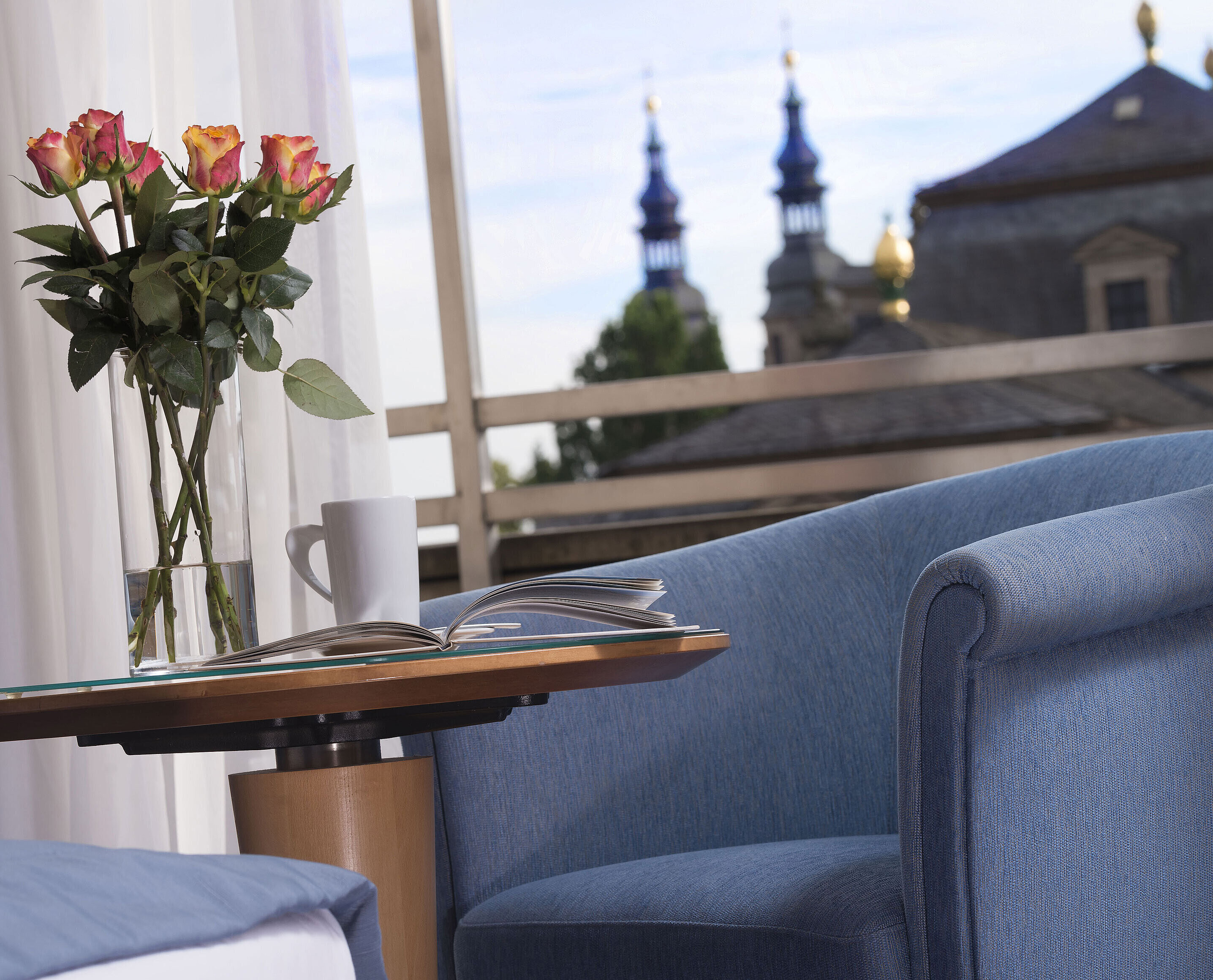 Zimmerdetail Elegantes Zimmerdetail im Maritim Hotel Fulda mit blauer Sitzgelegenheit, Rosen und Blick auf die barocken Türme von Fulda.