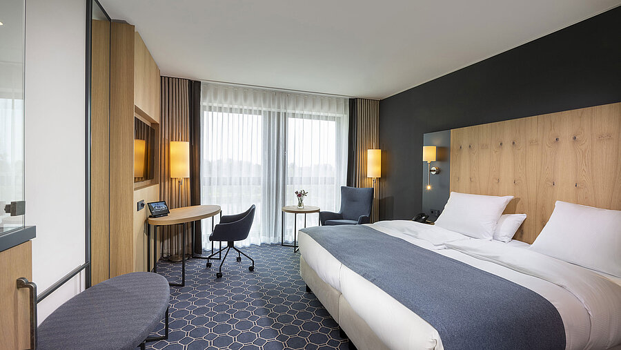 Geräumiges Doppelzimmer im Maritim Hotel Ingolstadt mit Schreibtisch, Sitzbereich und Balkon.