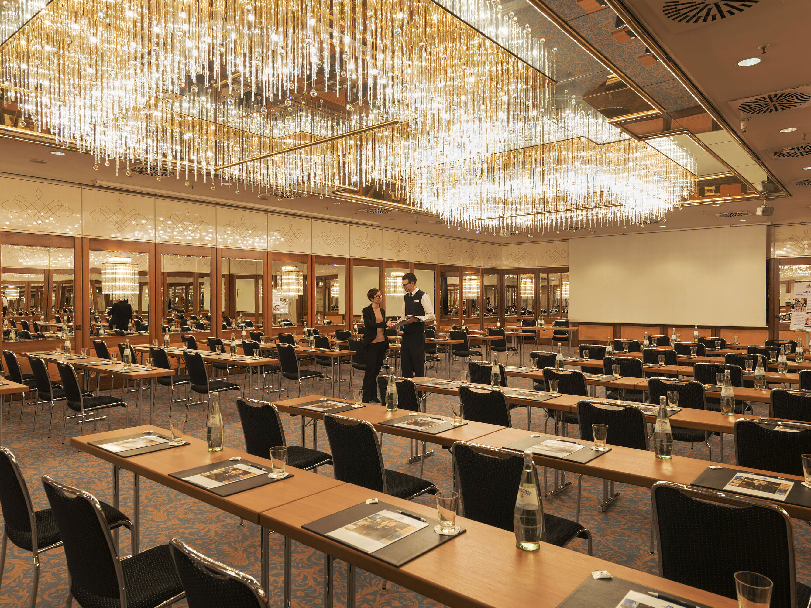 Großzügiger Konferenzsaal mit Kristallleuchtern und gespannter Atmosphäre im Maritim Hotel München