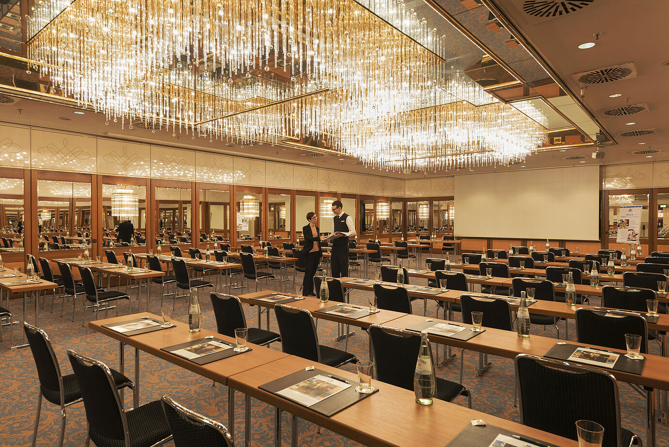Großzügiger Konferenzsaal mit Kristallleuchtern und gespannter Atmosphäre im Maritim Hotel München