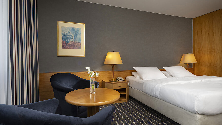 Hotelzimmer mit Doppelbett, gemütlicher Sitzecke und stilvoller Einrichtung, ideal für Entspannung