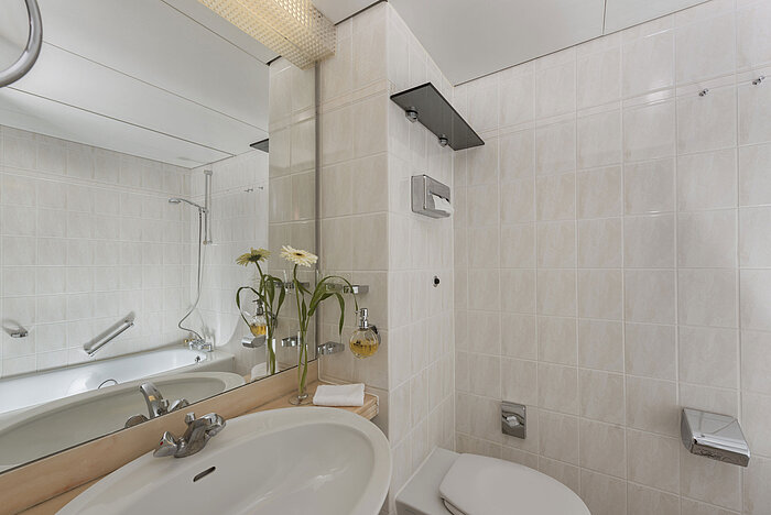 Helles Bad im Maritim Hotel Bad Salzuflen mit Dusche, großem Spiegel und weißen Fliesen