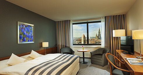 Zimmer im Maritim Hotel Ulm mit Doppelbett, Sitzbereich und Panoramablick auf das Ulmer Münster