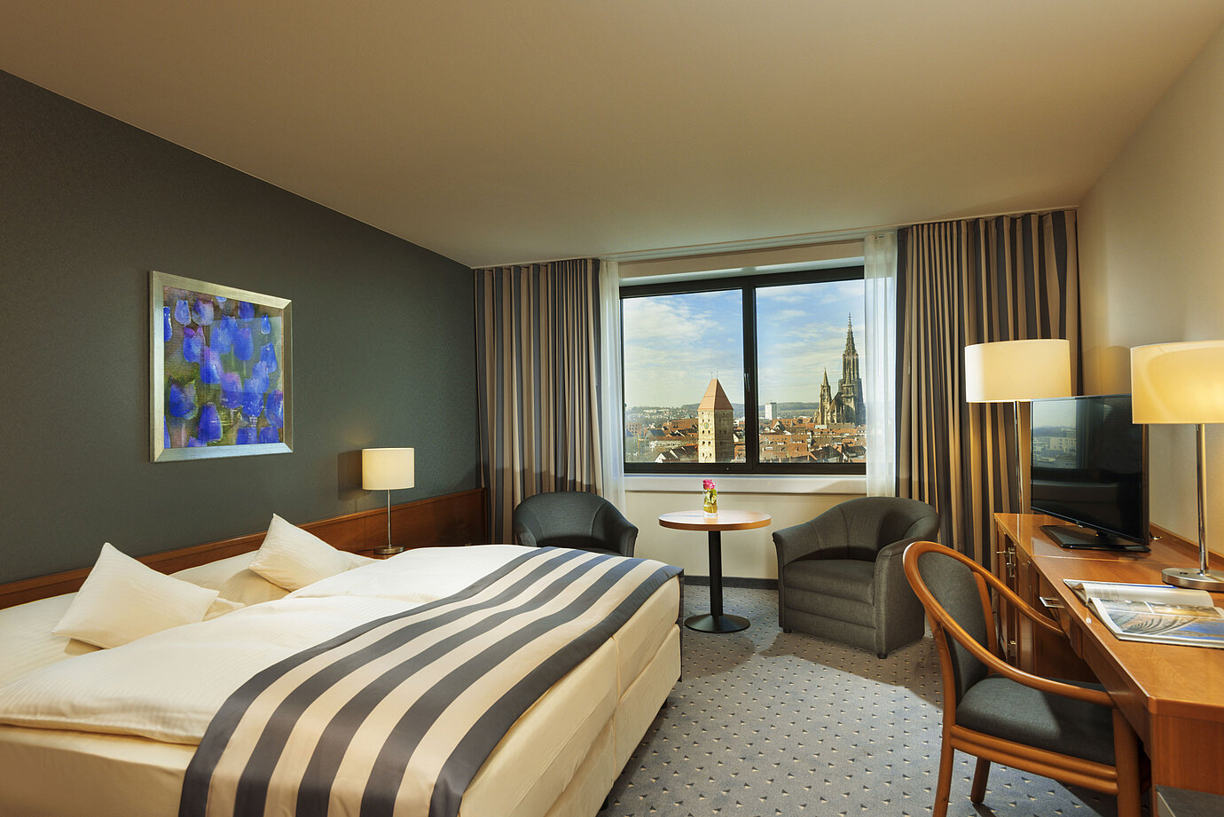 Zimmer im Maritim Hotel Ulm mit Doppelbett, Sitzbereich und Panoramablick auf das Ulmer Münster