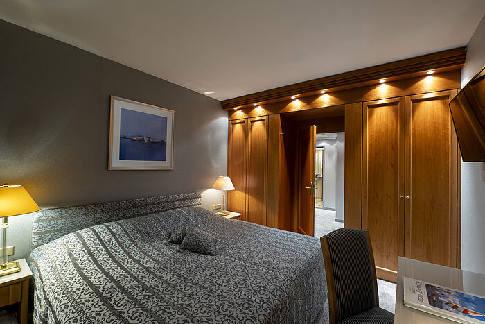 Schlafbereich der Grand Suite im Maritim Hotel Kiel mit stilvollem Design, großem Bett und eleganter Beleuchtung.