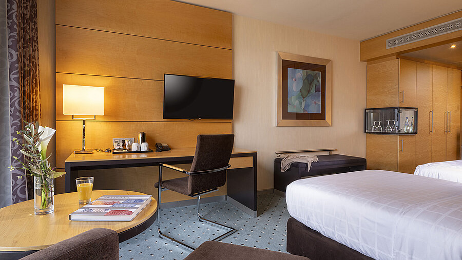 Classic Zimmer im Maritim Hotel Düsseldorf mit Schreibtisch, Flachbild-TV, Doppelbett und eleganter Einrichtung.