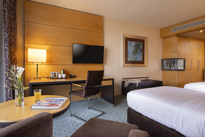 Classic Zimmer im Maritim Hotel Düsseldorf mit Schreibtisch, Flachbild-TV, Doppelbett und eleganter Einrichtung.