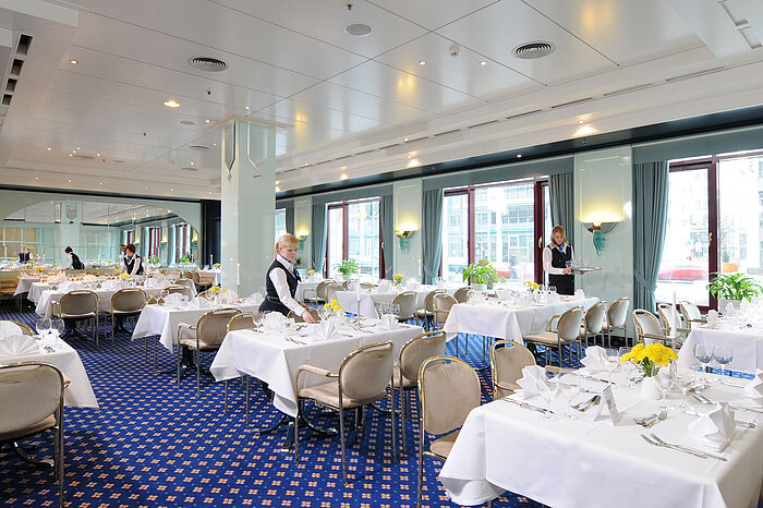 Tagungsraum Salon Bonn im Maritim Hotel Magdeburg mit weiß gedeckten Tischen, eleganter Dekoration und freundlichem Servicepersonal.