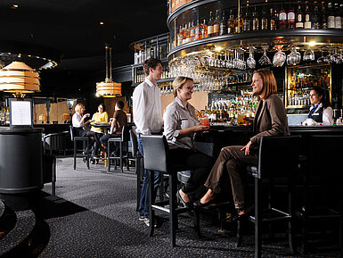 Gäste genießen Drinks und Gespräche in der stilvollen Bar des Maritim Hotel München
