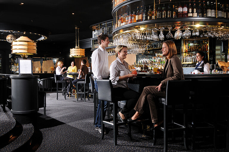 Gäste genießen Drinks und Gespräche in der stilvollen Bar des Maritim Hotel München