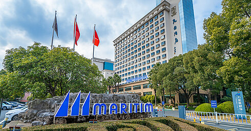 Außenansicht des Maritim Hotels mit großem Logo, gepflegten Grünanlagen und Flaggen vor dem Hoteleingang