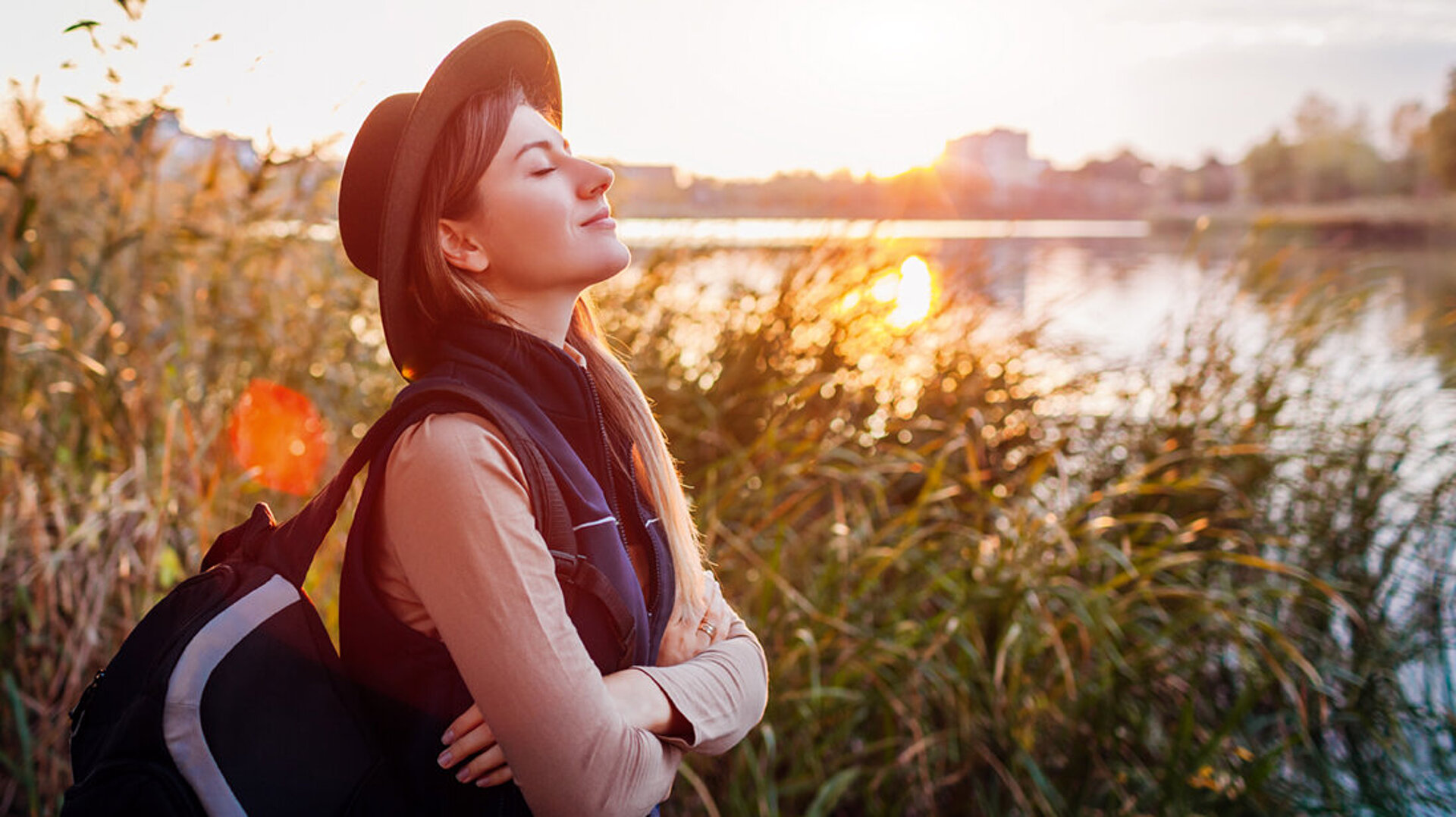 Frau entspannt am Seeufer bei Sonnenuntergang und genießt die Natur
