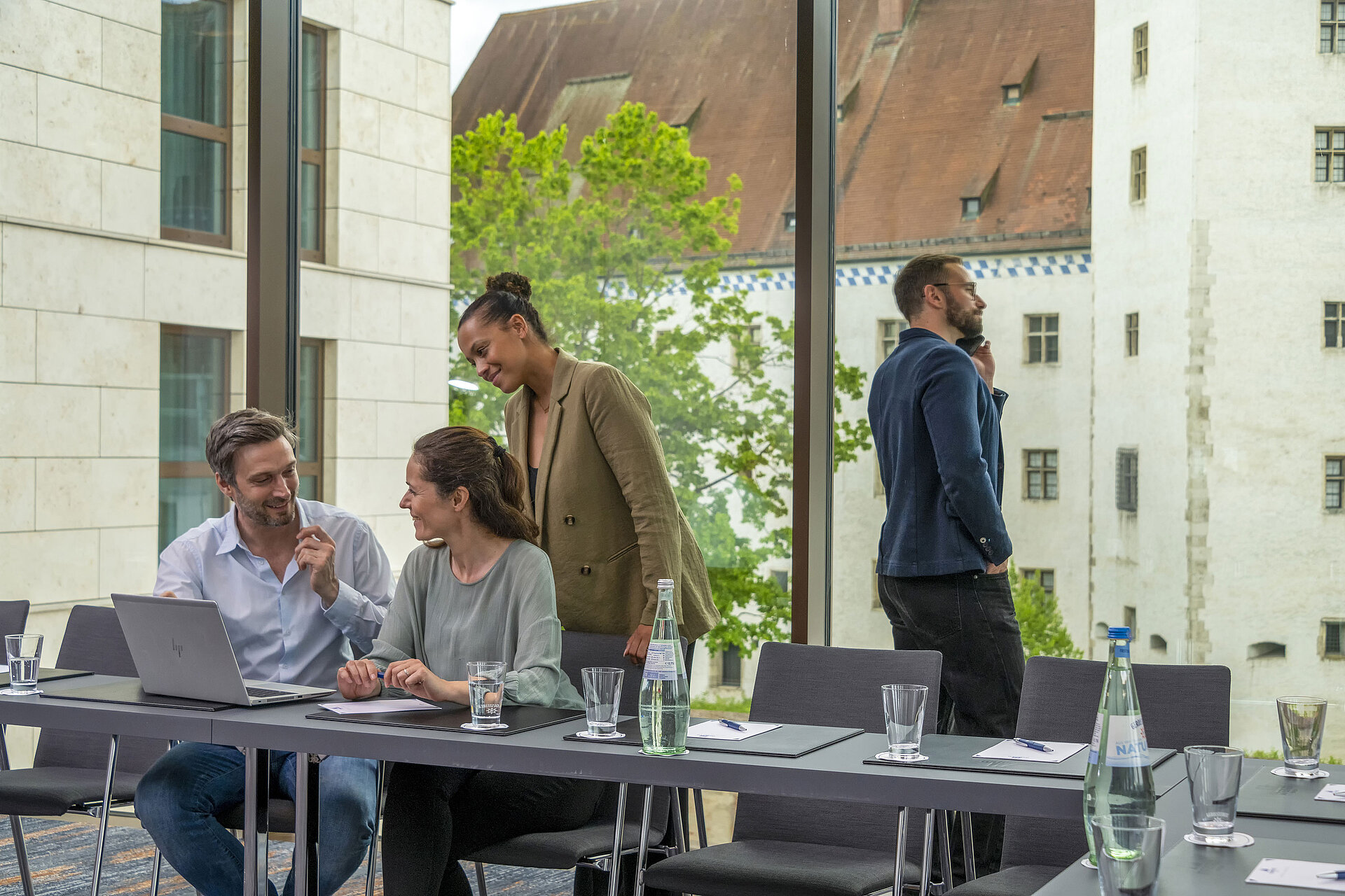 Tagungsraum Lächelnde Geschäftsleute im Tagungsraum des Maritim Hotel Ingolstadt mit Blick auf historische Gebäude.