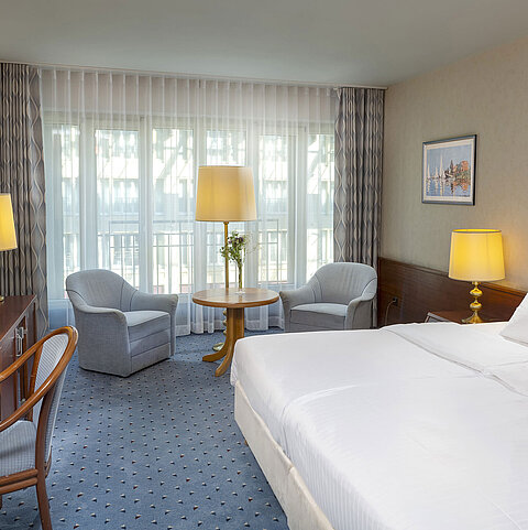 Classic Zimmer im Maritim Hotel Köln mit Doppelbett, gemütlicher Sitzgelegenheit, Schreibtisch und TV.