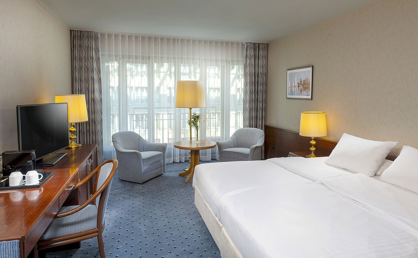Classic Zimmer im Maritim Hotel Köln mit Doppelbett, gemütlicher Sitzgelegenheit, Schreibtisch und TV.