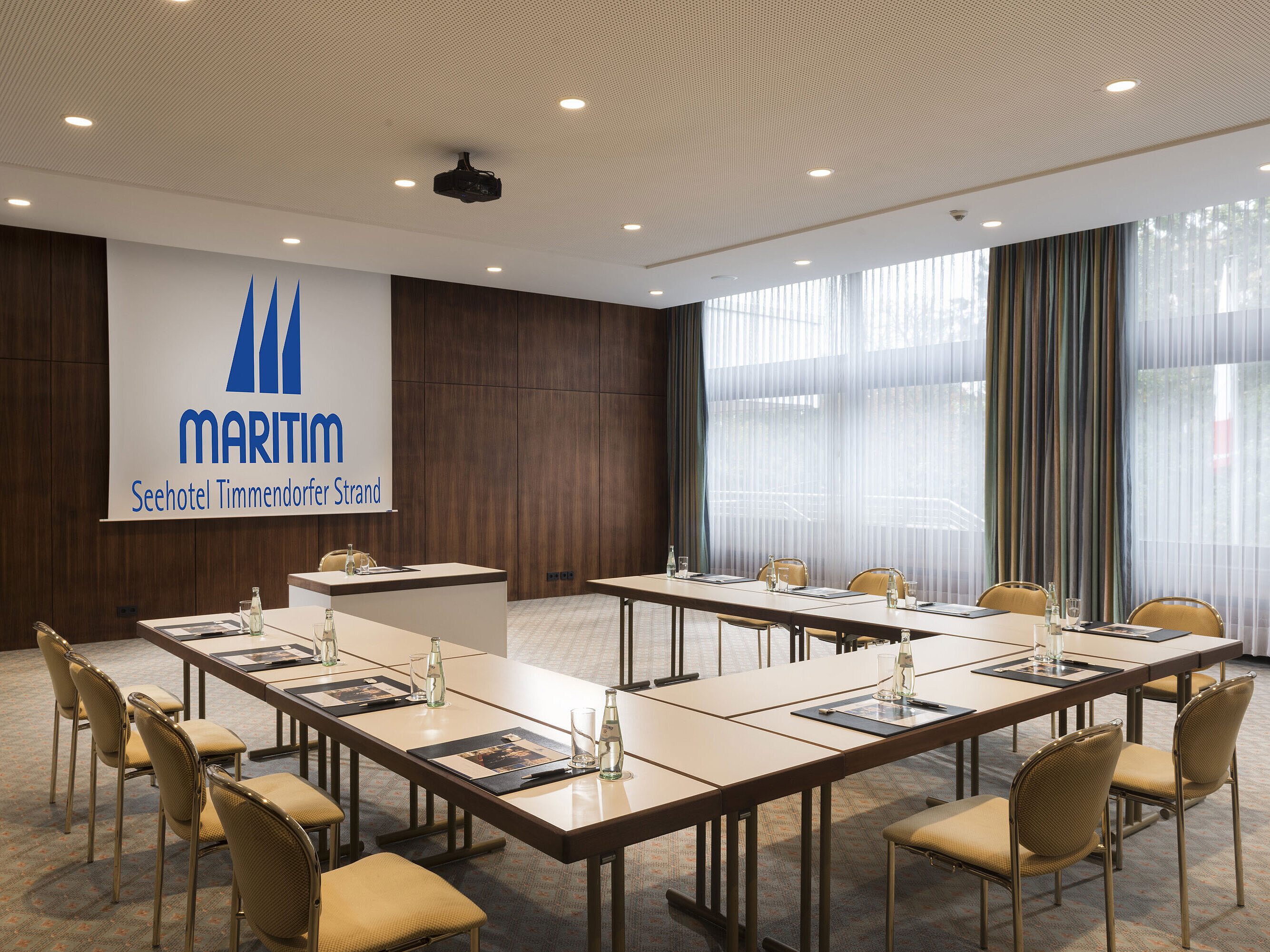Konferenzraum „Salon Köln“ im Maritim Seehotel Timmendorfer Strand mit U-förmiger Bestuhlung und Tageslicht.