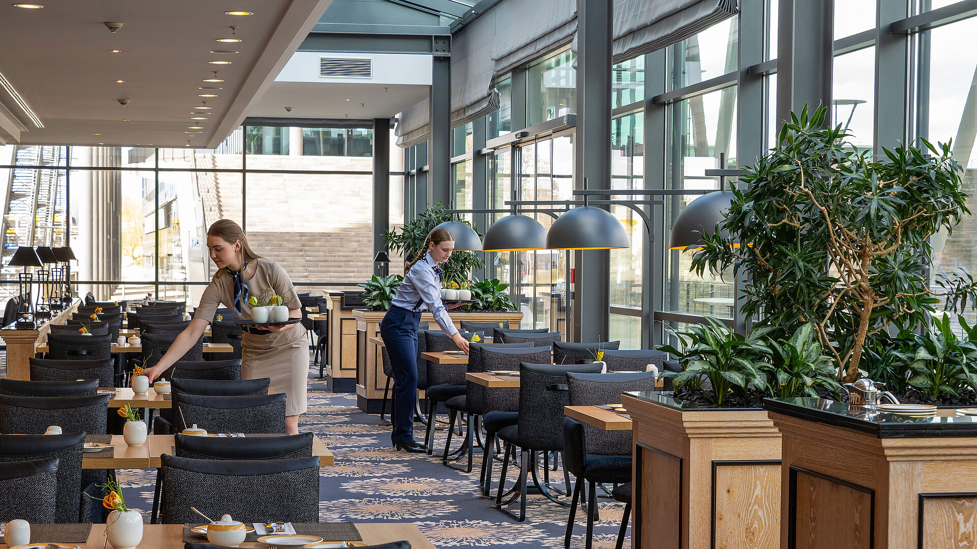 Heller Restaurantbereich Wintergarten im Maritim Hotel Dresden mit großen Fensterfronten und stilvoll gedeckten Tischen.