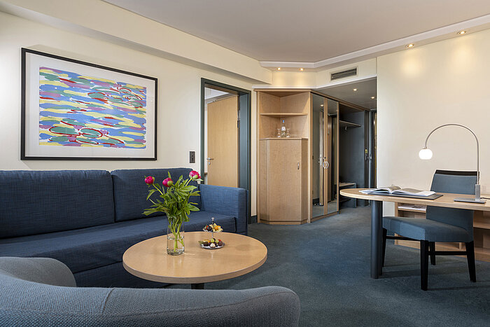 Moderne Suite mit Sofa, Schreibtisch und stilvollem Kunstwerk im Maritim proArte Hotel Berlin.