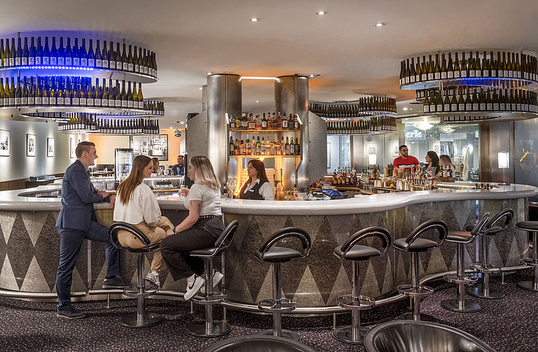 Elegante Bar im Maritim Berlin, in der Gäste entspannte Gespräche genießen und eine große Auswahl an Getränken geboten wird.