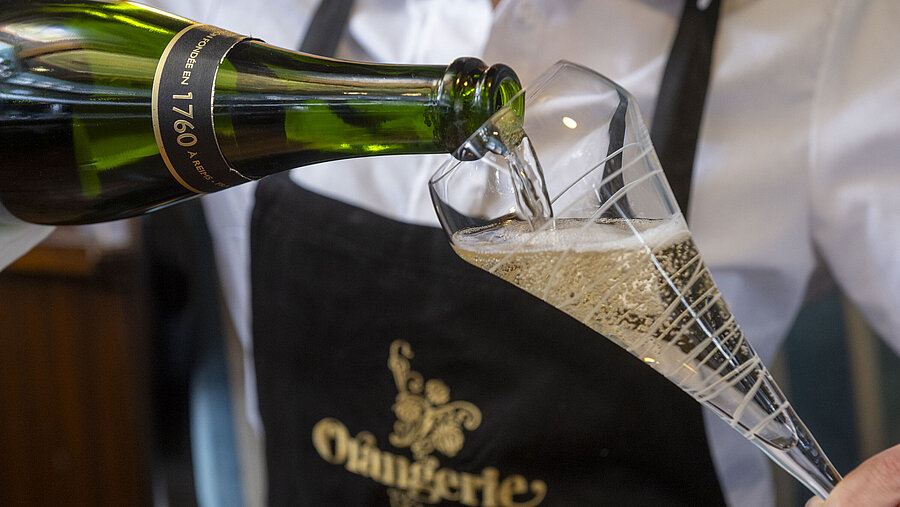 Champagner wird in ein Glas im Restaurant Orangerie im Maritim Timmendorfer Strand eingeschenkt.