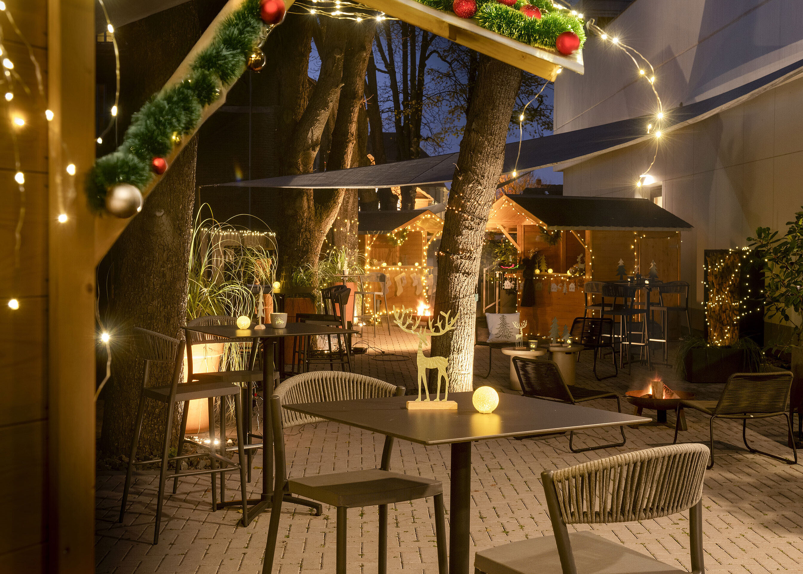 Festlich geschmückter Weihnachtsmarkt im Maritim Hotel Darmstadt mit Lichterketten, dekorierten Hütten und einem Schneemann.
