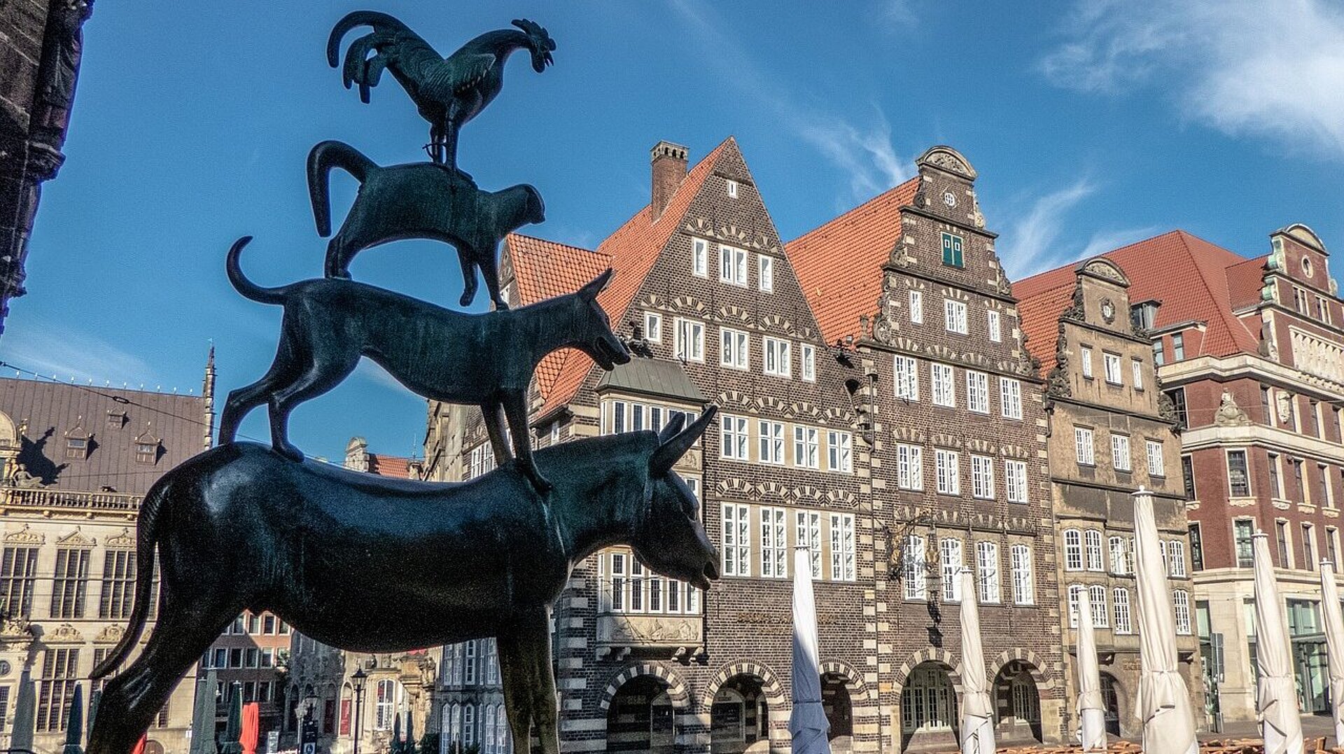 Bronzeskulptur der Bremer Stadtmusikanten auf dem Marktplatz in Bremen vor historischen Gebäuden der Altstadt.