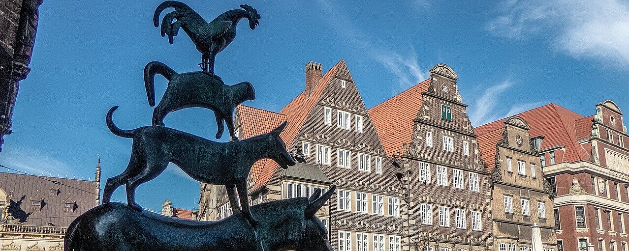 Bronzeskulptur der Bremer Stadtmusikanten auf dem Marktplatz in Bremen vor historischen Gebäuden der Altstadt.